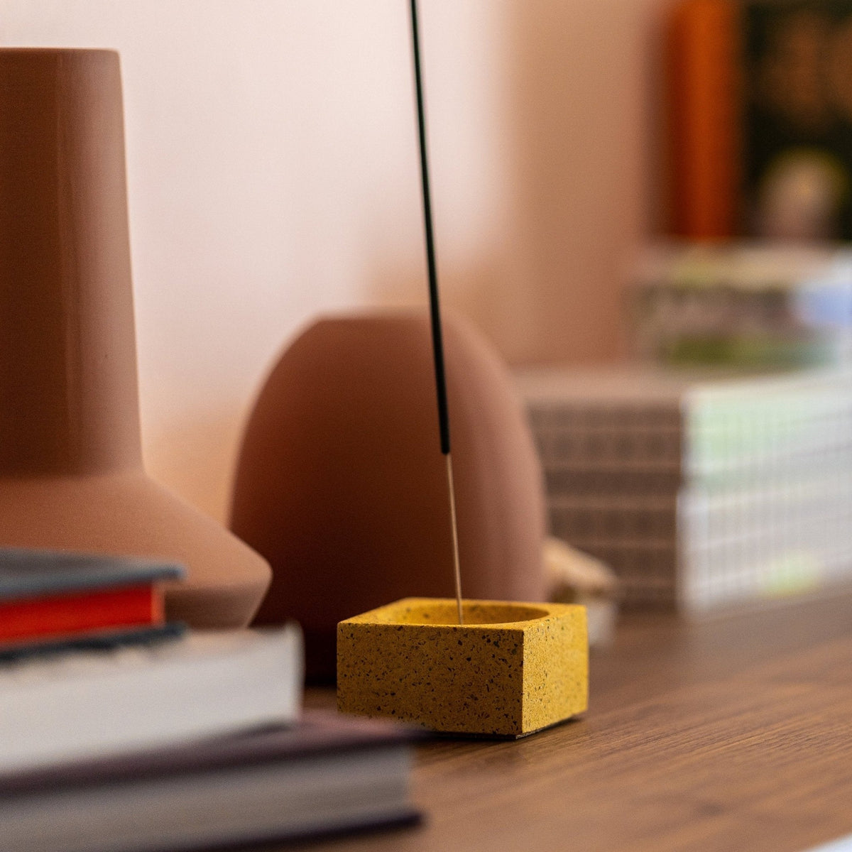 Square Incense Holder in Marigold Terrazzo with a lit incense stick on a desk
